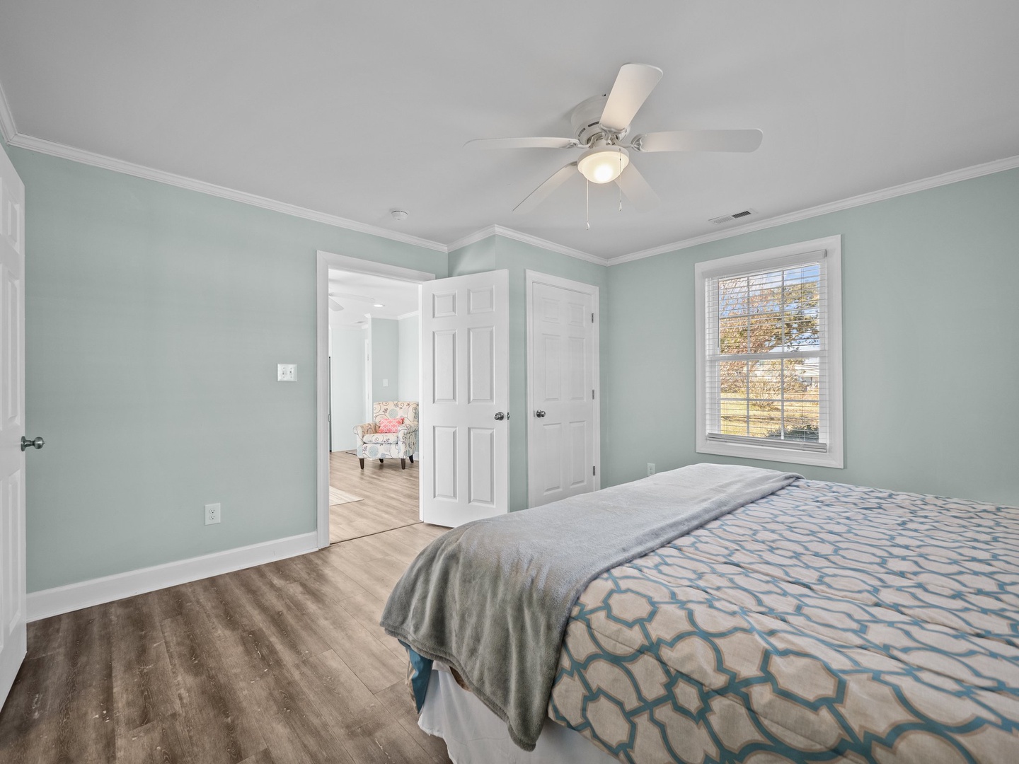 Your peaceful bedroom features soothing mint walls and polished hardwood floors, with a ceiling fan for comfort and charming window views.