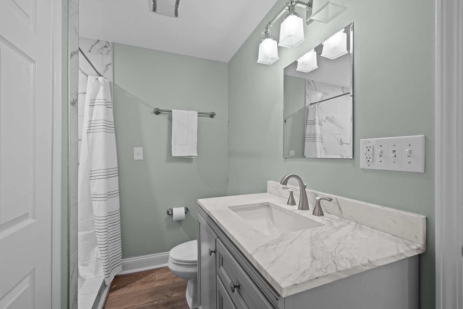 Refresh in your elegant bathroom featuring crisp marble countertops, soft sage walls, and plush towels waiting for you.