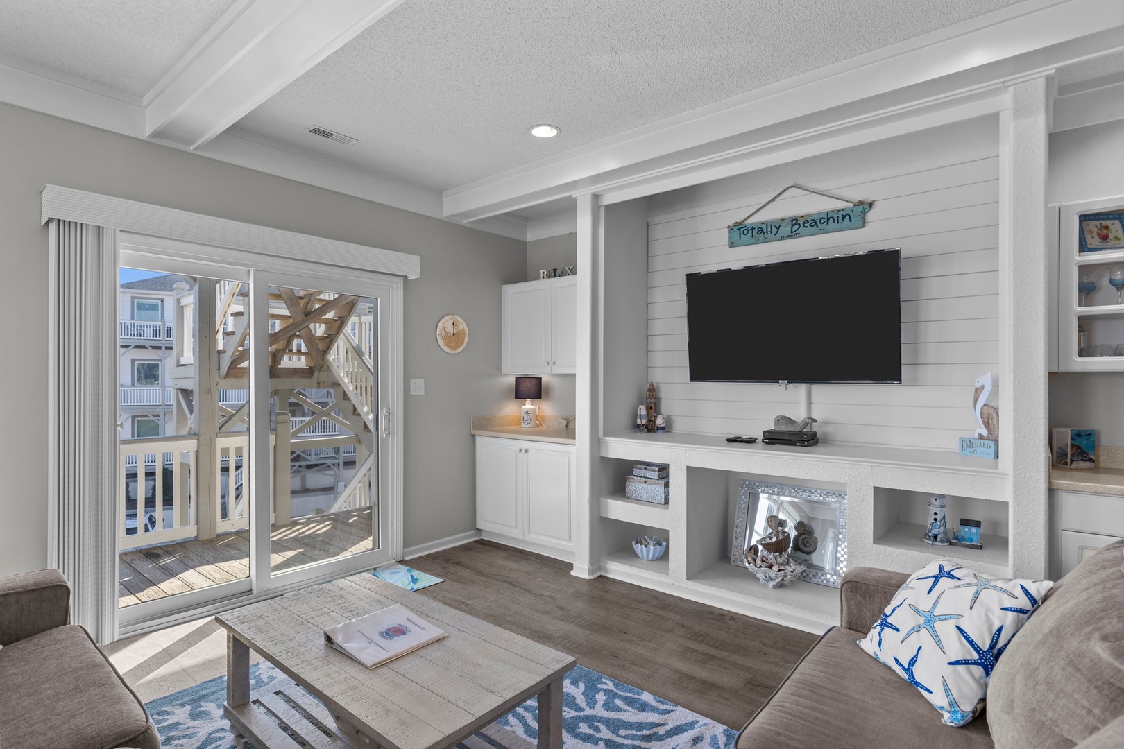 Relax in your coastal living room with shiplap accent wall, built-in entertainment center, and sliding doors opening to your private deck.