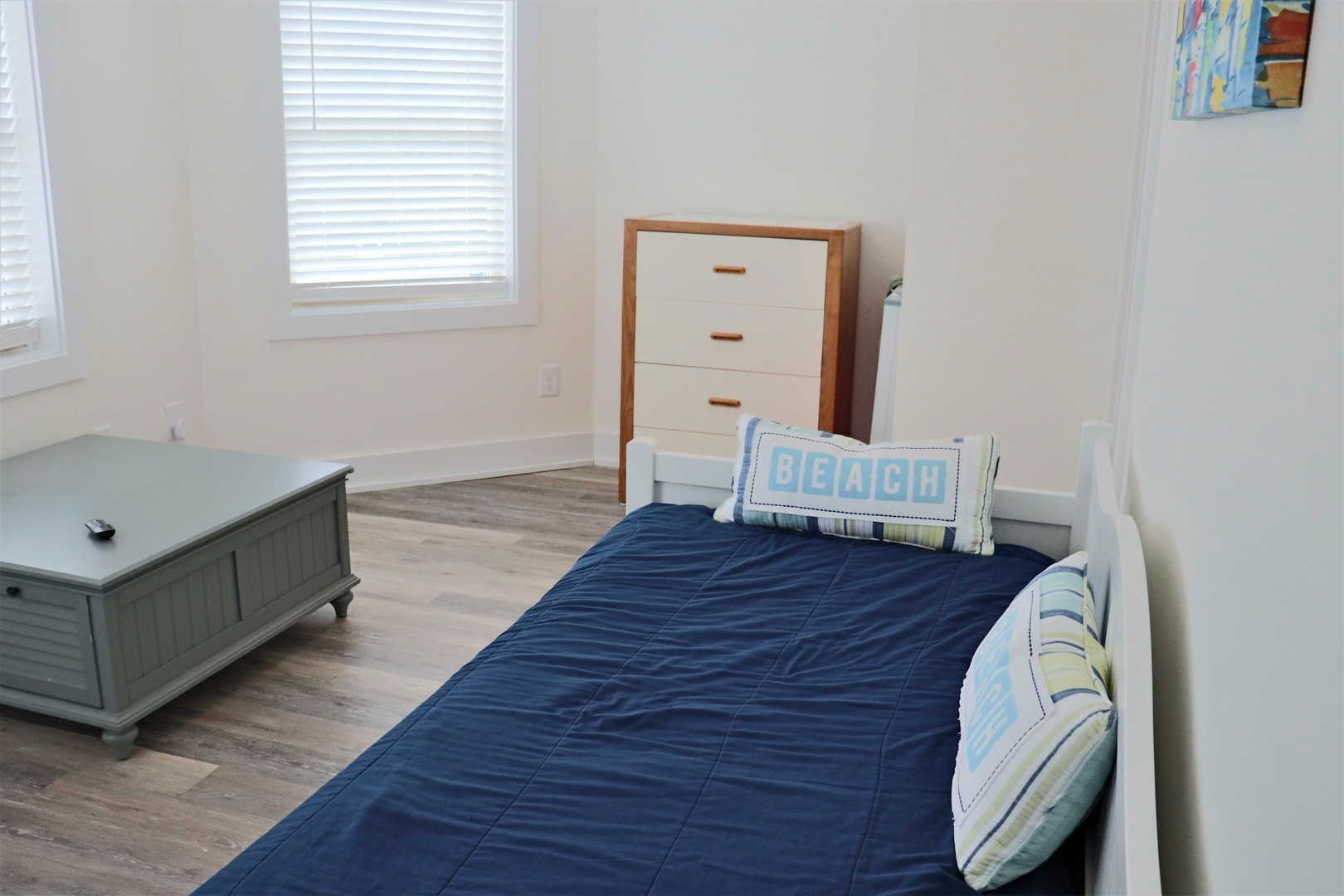 Your coastal-themed bedroom features a comfortable twin bed with beach-inspired blue linens and nautical pillows, creating a serene space for rest.
