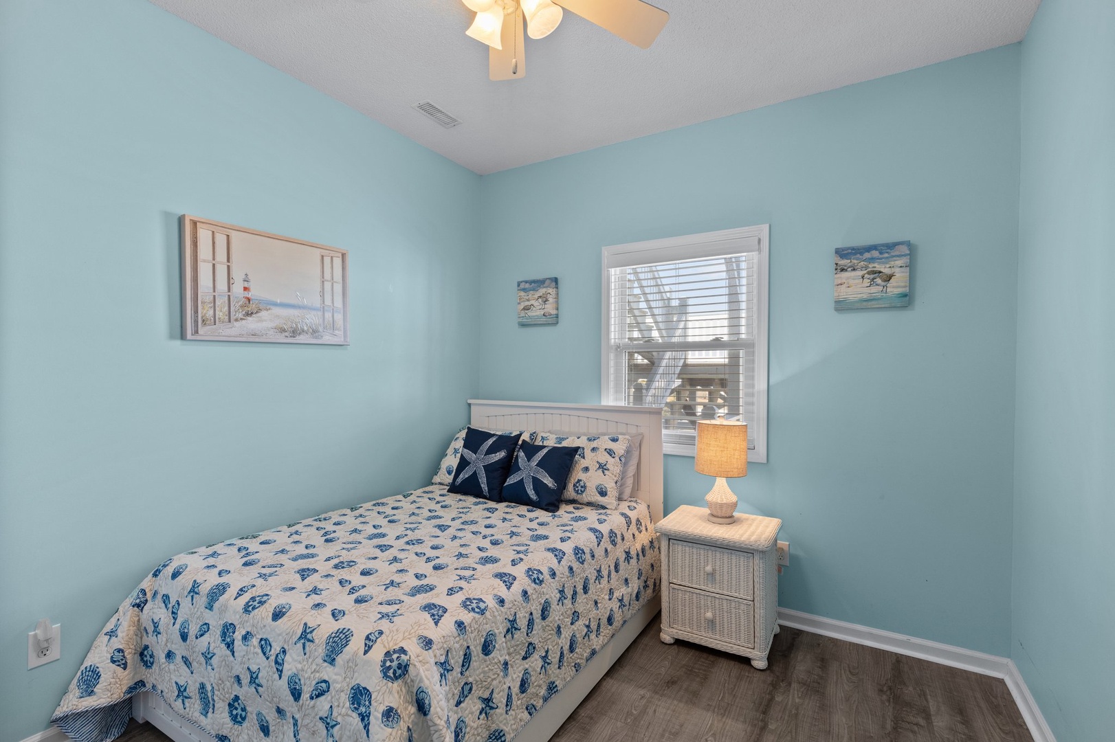 Drift off to sleep in your cozy coastal bedroom, where soothing blue walls and sea-themed bedding create the perfect beach house retreat.