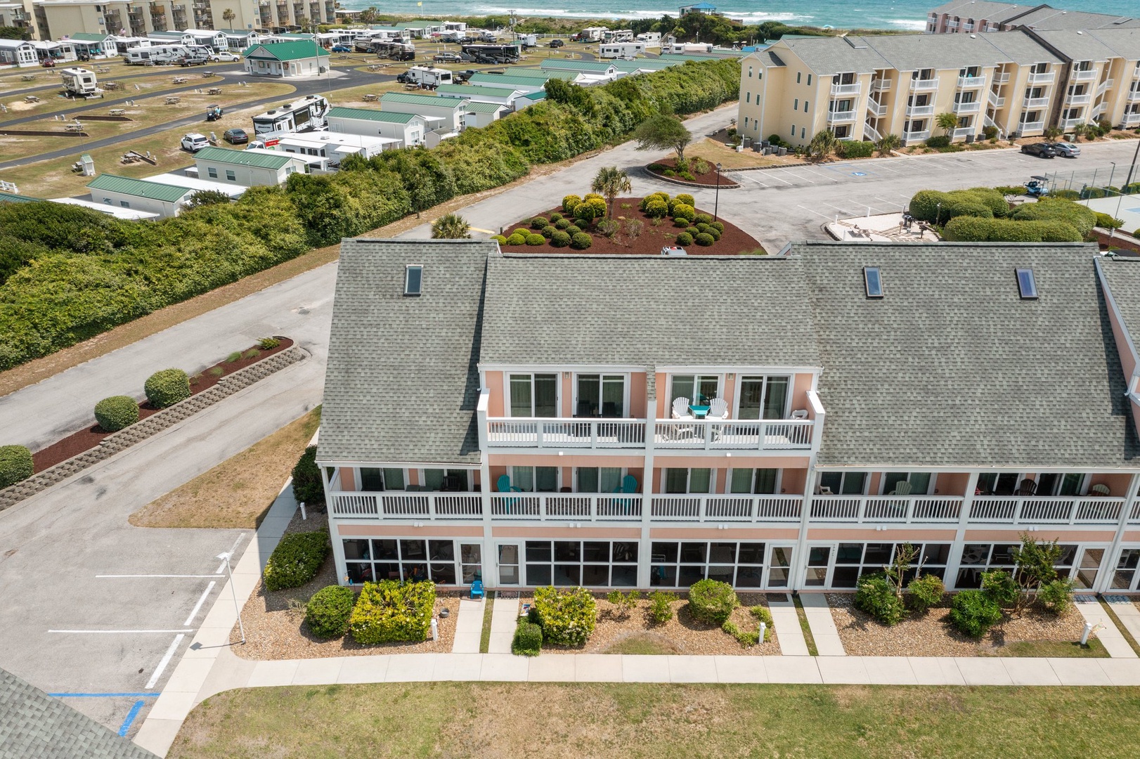 This coastal property sits just steps from the ocean, surrounded by charming beachside buildings and lush landscaping.