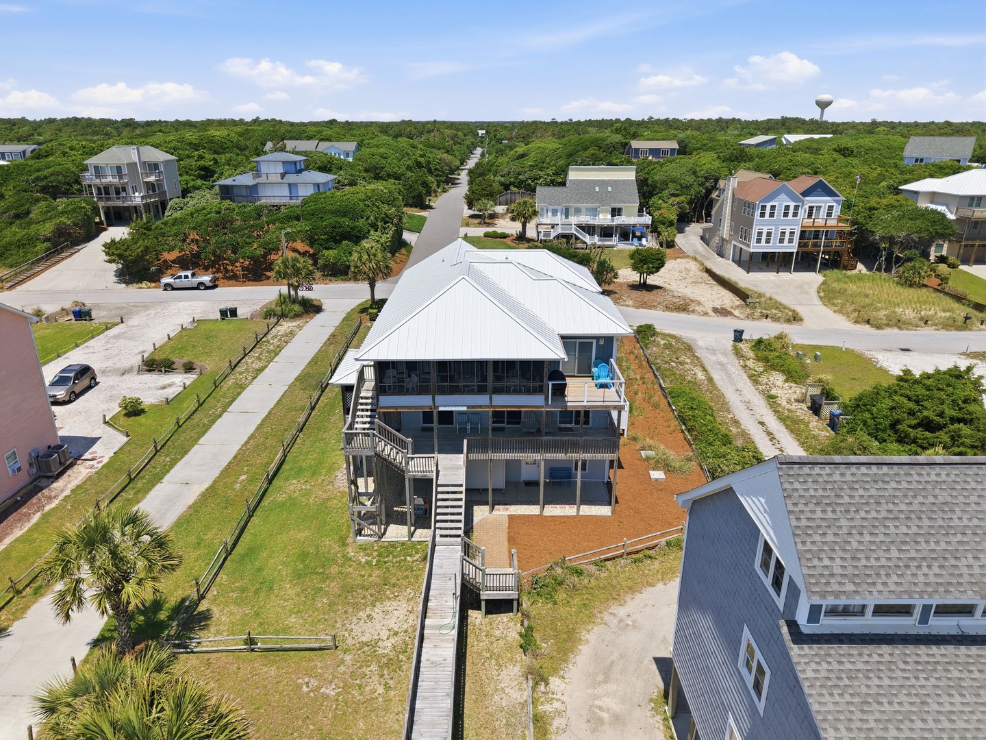 Elevated vacation home nestled in a quiet coastal neighborhood, surrounded by lush greenery and just moments from the beach with convenient parking and outdoor access.