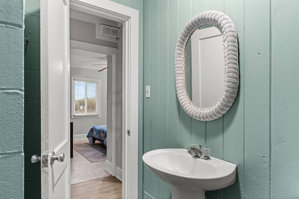Freshen up in this charming powder room with coastal-inspired teal paneling and elegant oval mirror—perfect for your morning routine.