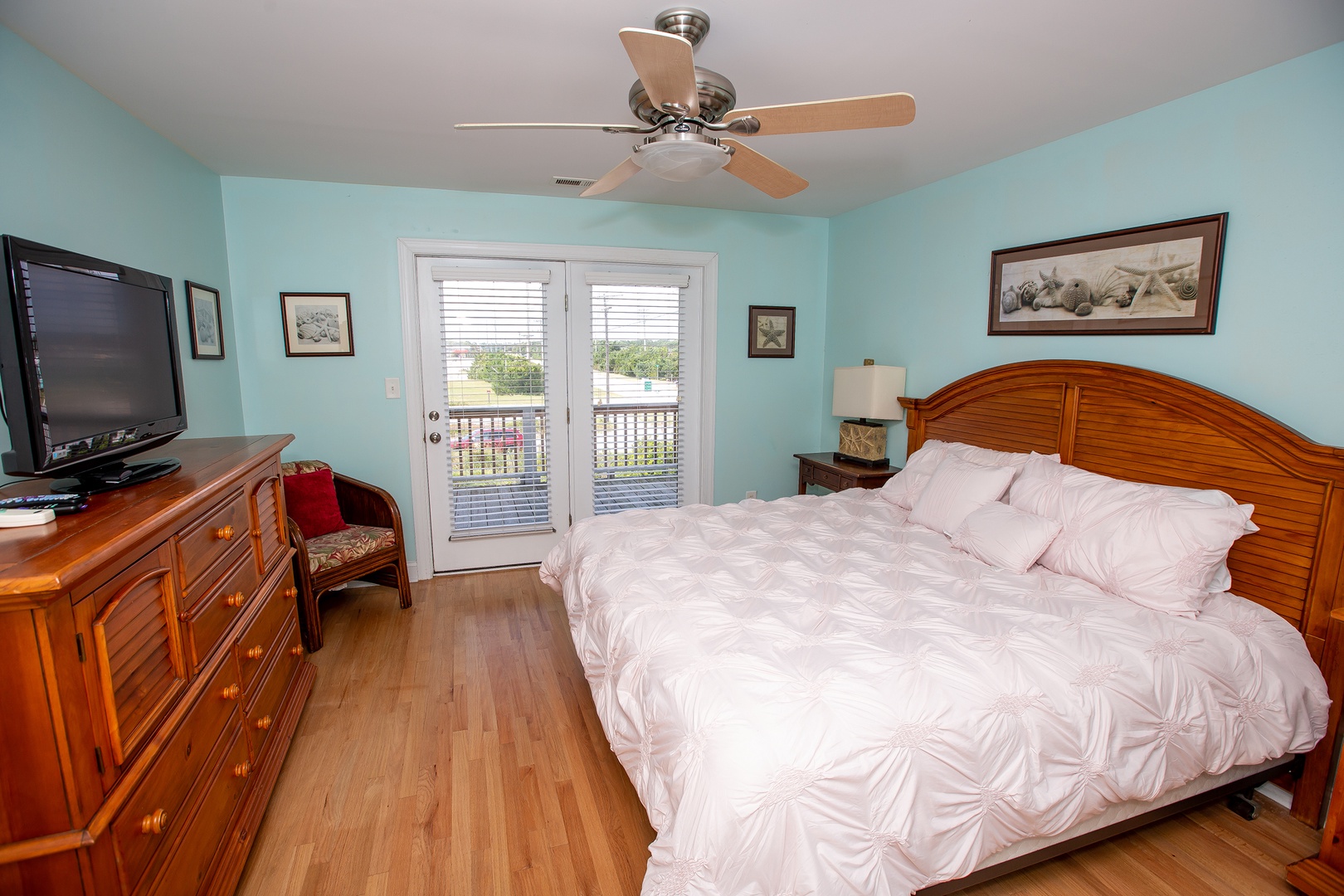 Drift off in this serene bedroom with coastal décor, ceiling fan, and French doors opening to your private balcony.