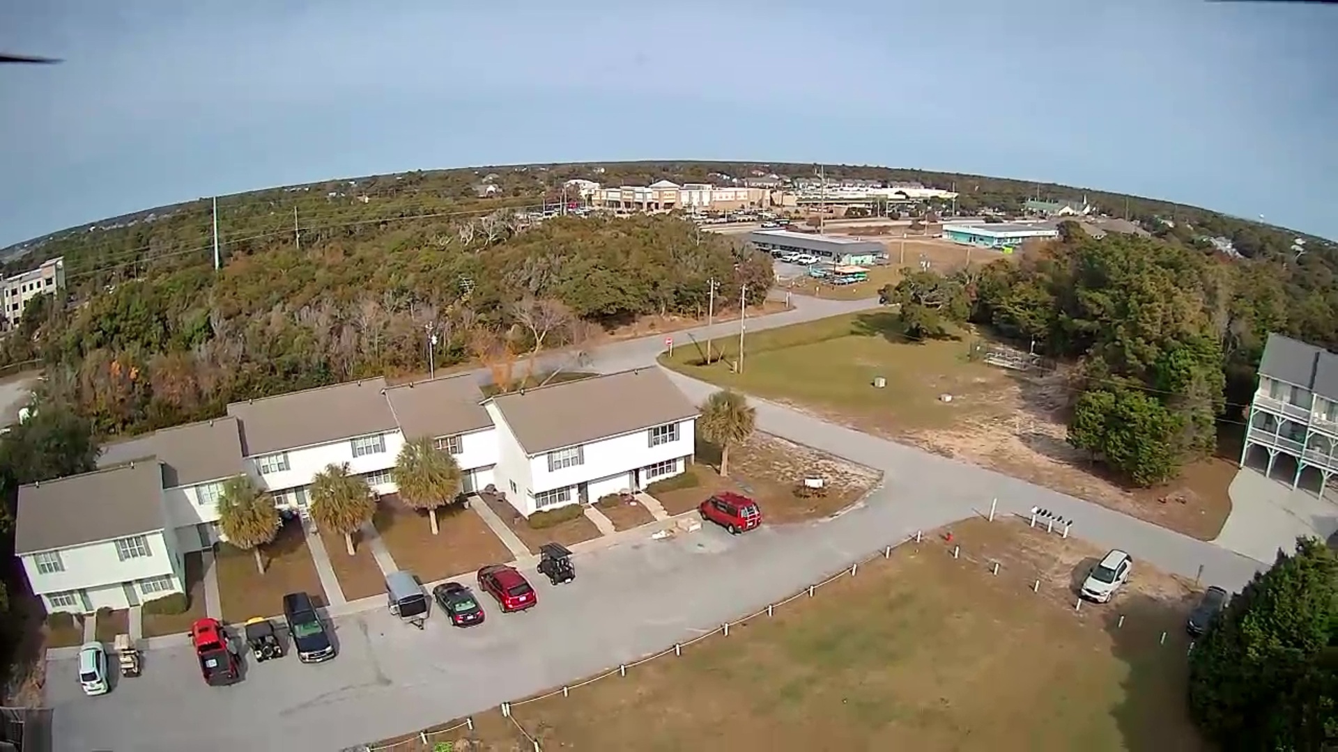 Aerial view of the property showcasing the main building complex surrounded by lush greenery and ample parking facilities.