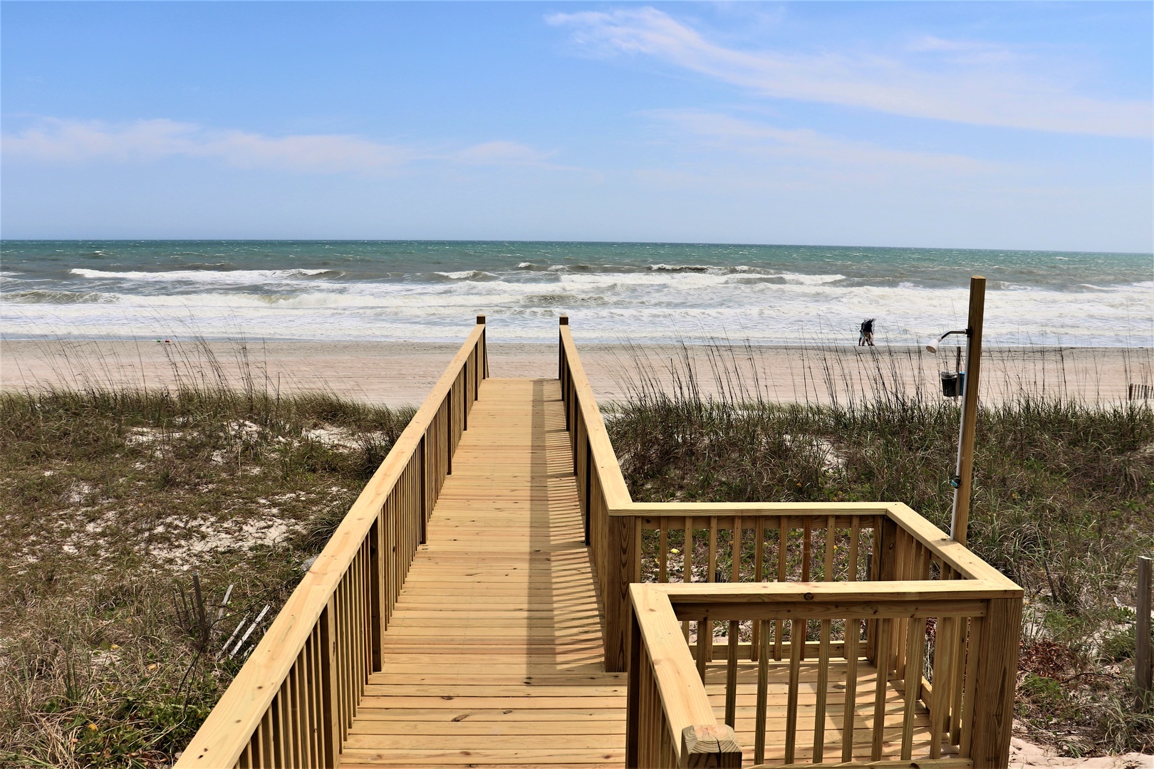 Private wooden boardwalk leads directly to pristine sandy beach with rolling waves and endless ocean views.