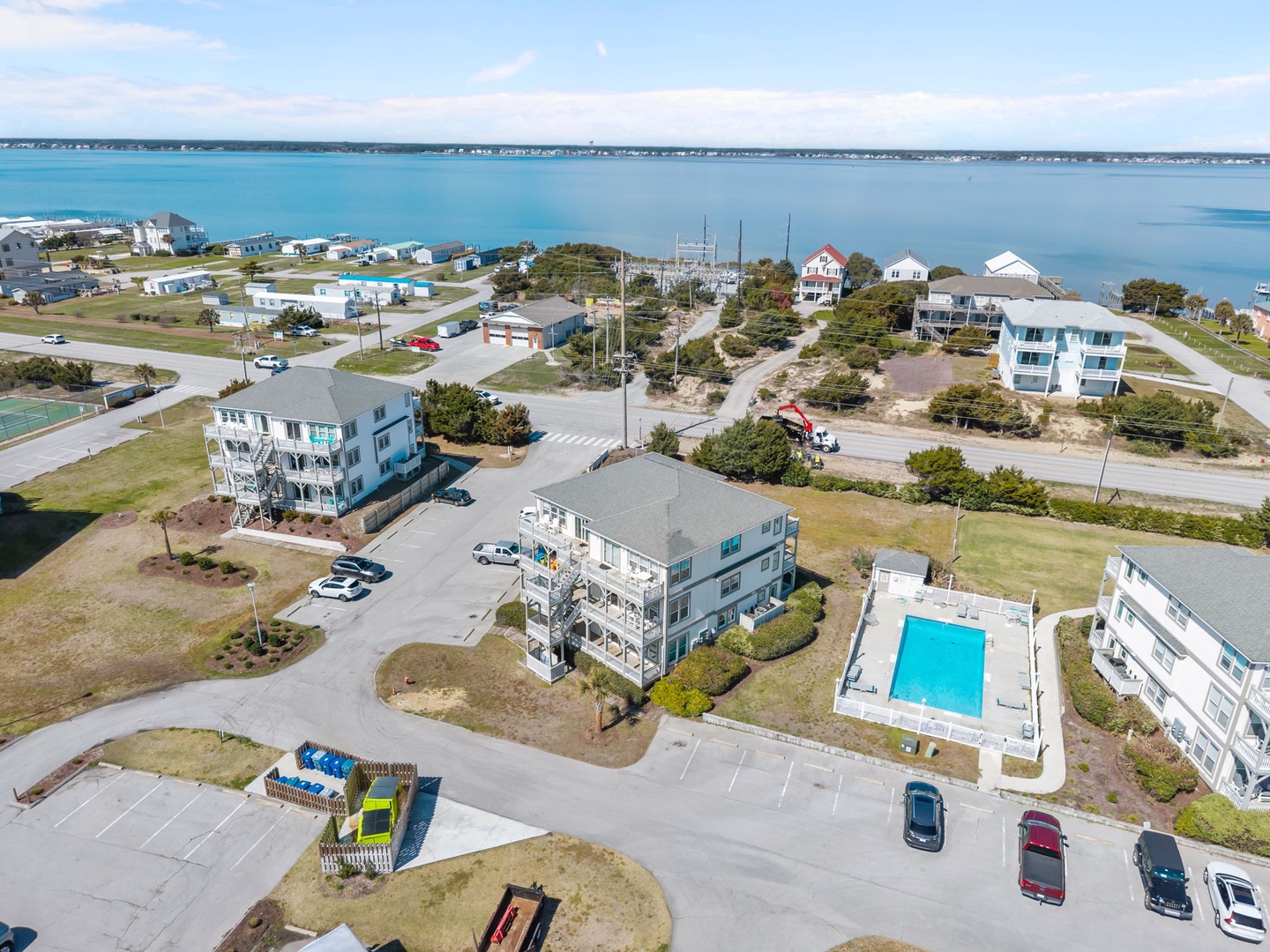 Aerial view of beachfront vacation rental community featuring multi-story homes, swimming pool, and stunning ocean access.