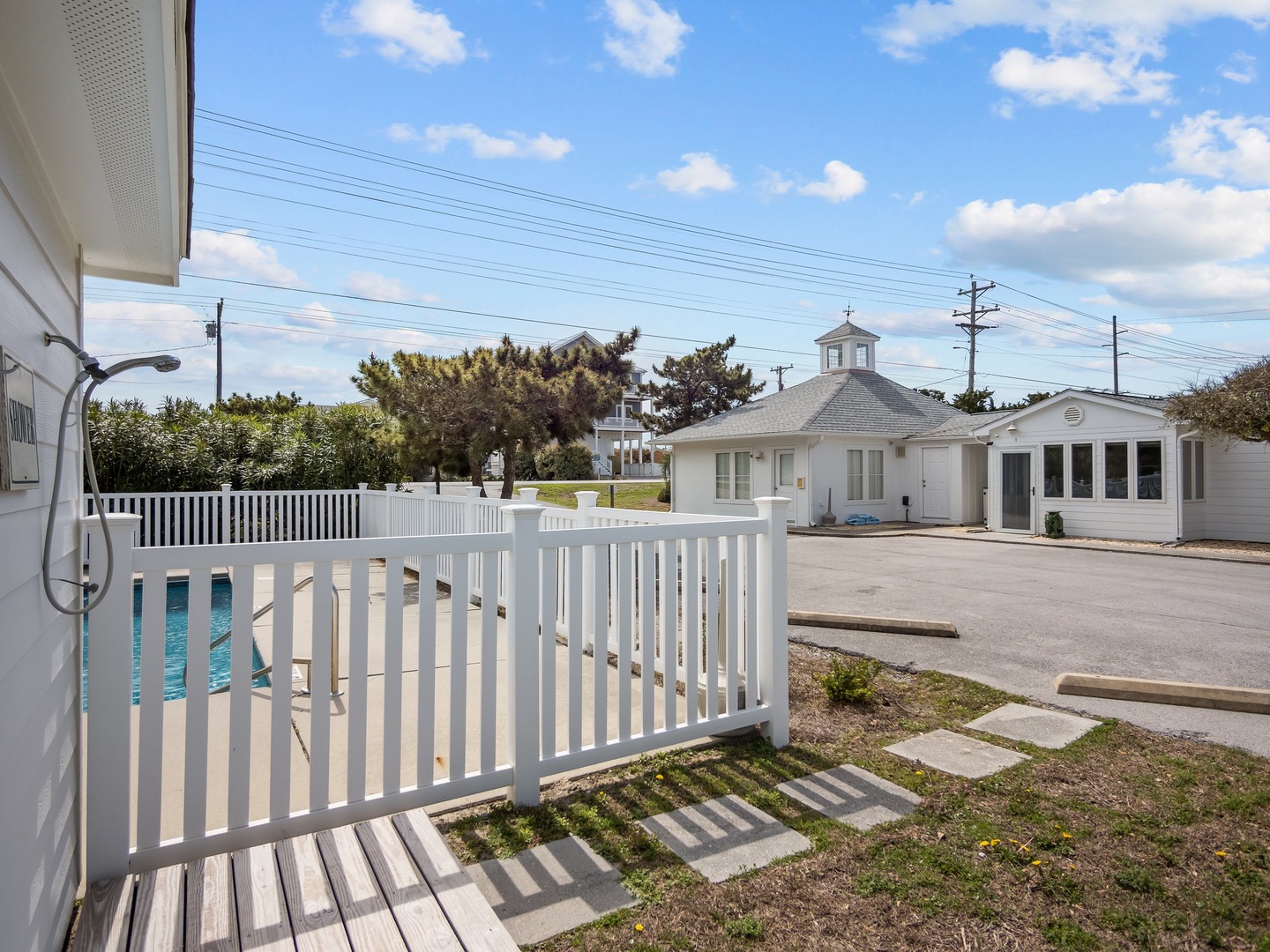 Property exterior features charming white buildings and a fenced pool area in a peaceful residential setting.