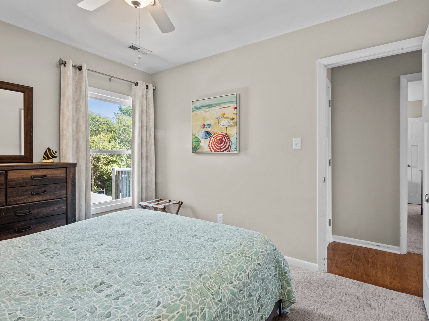 Sink into your cozy bedroom retreat with comfortable bedding, peaceful views, and charming beach artwork that sets the perfect vacation mood.