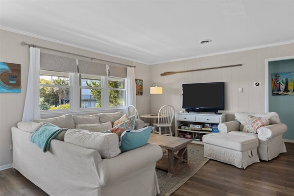 Sink into plush sofas with colorful pillows while watching your favorite shows on the large TV in this bright, coastal-themed living space.