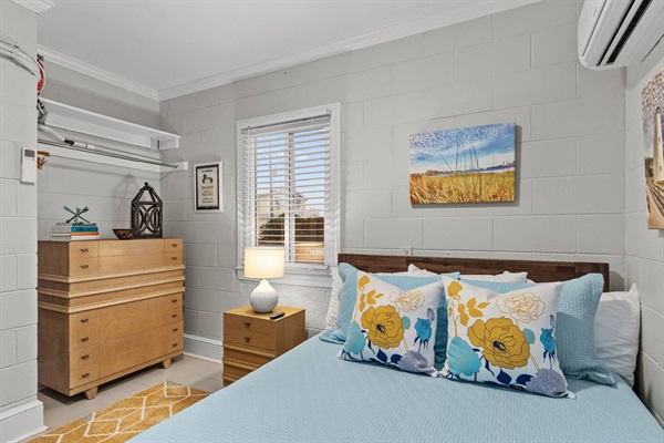 Drift off peacefully in your cozy bedroom with soft blue linens, natural light, and coastal artwork creating a serene retreat.