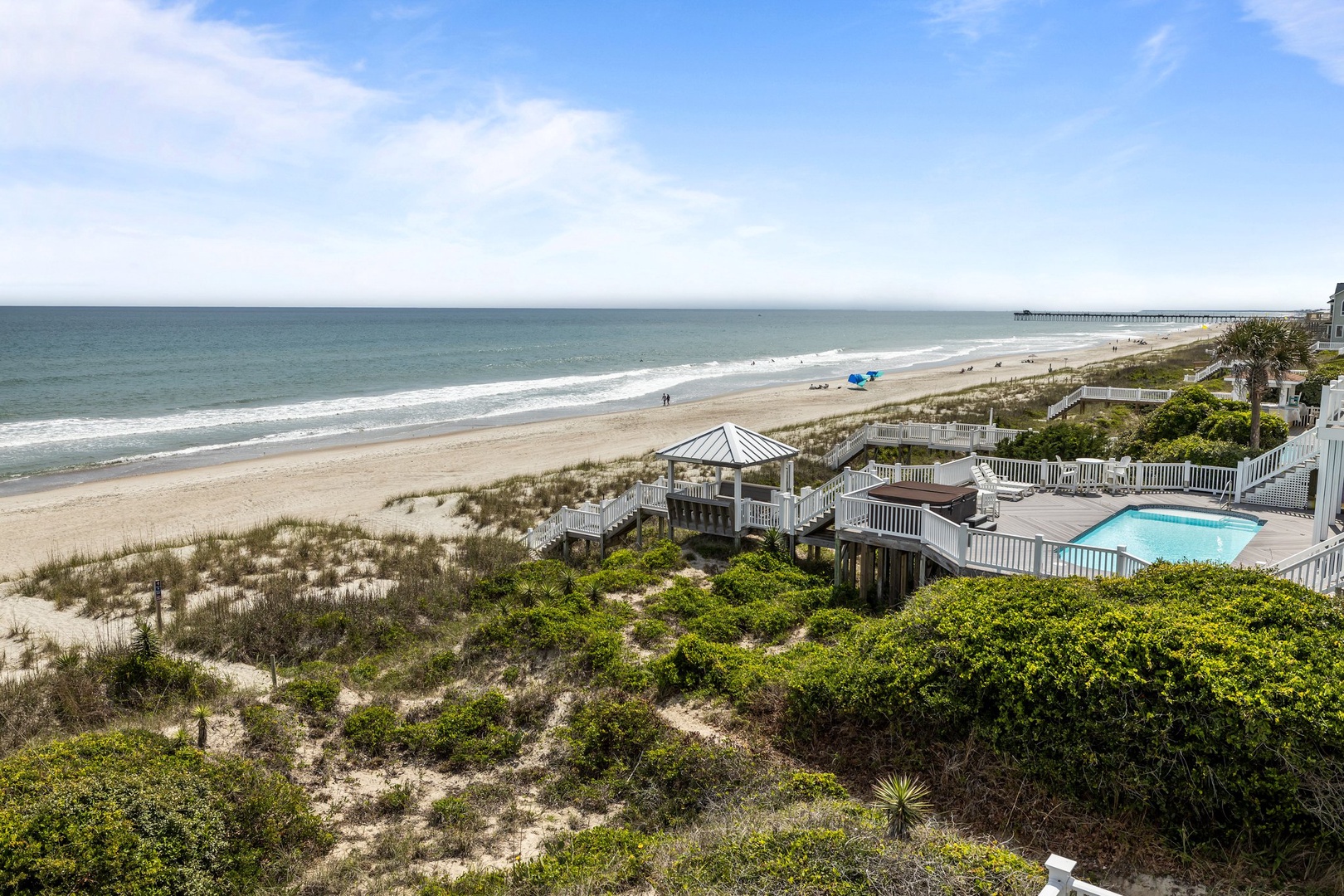 Oceanfront vacation home with private pool and beach boardwalk access, surrounded by natural dunes and coastal vegetation.