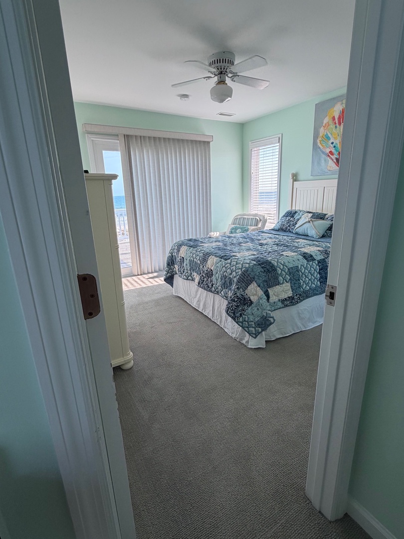 Sink into your comfortable bed with coastal-themed linens and enjoy natural light streaming through the window blinds in your peaceful retreat.