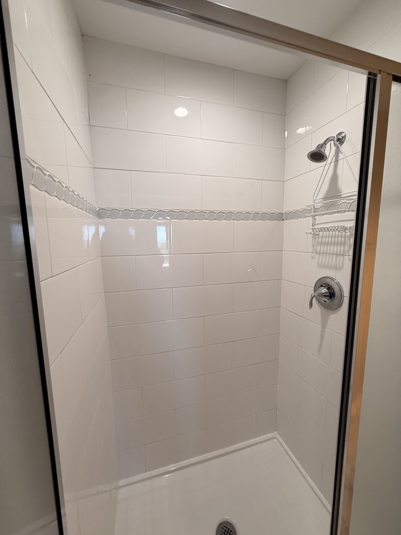 Sleek, modern walk-in shower with dual showerheads and pristine white tiling—your private retreat for refreshing mornings or unwinding after a day of adventure.