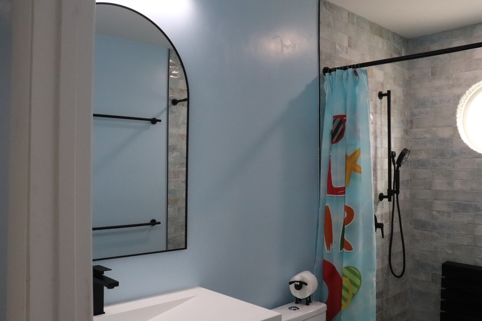 Relax in your modern bathroom with a sleek walk-in shower, fresh towels, and playful beach-themed touches adding character to your coastal retreat.