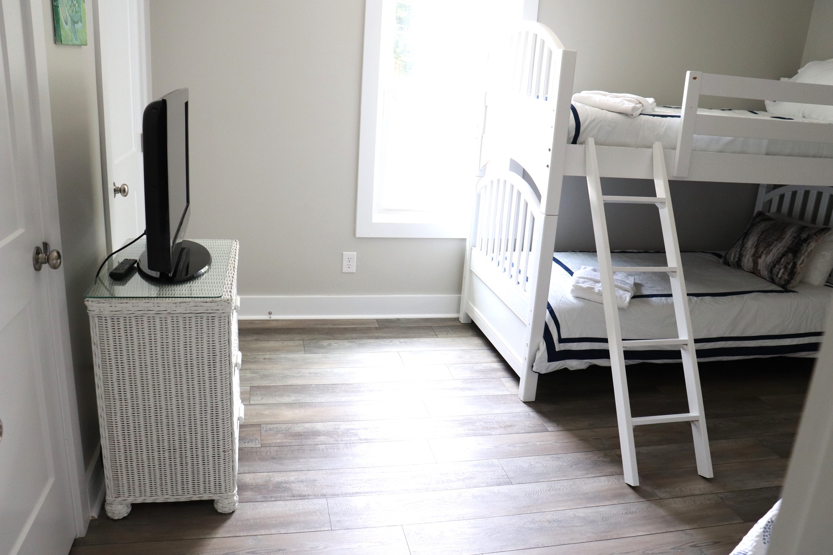 Your kids will love this bright bedroom featuring sturdy white bunk beds with comfortable bedding and natural light streaming through the window.