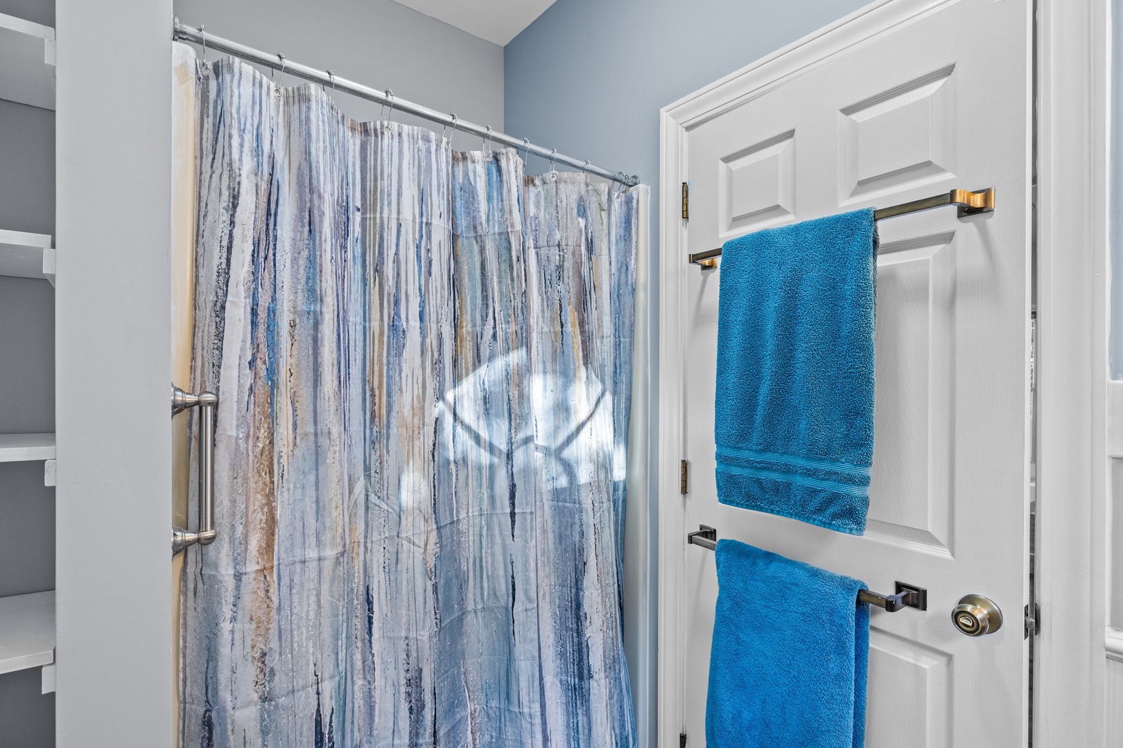 Step into your private bathroom featuring a refreshing shower with coastal-inspired curtains and plush blue towels waiting for you.