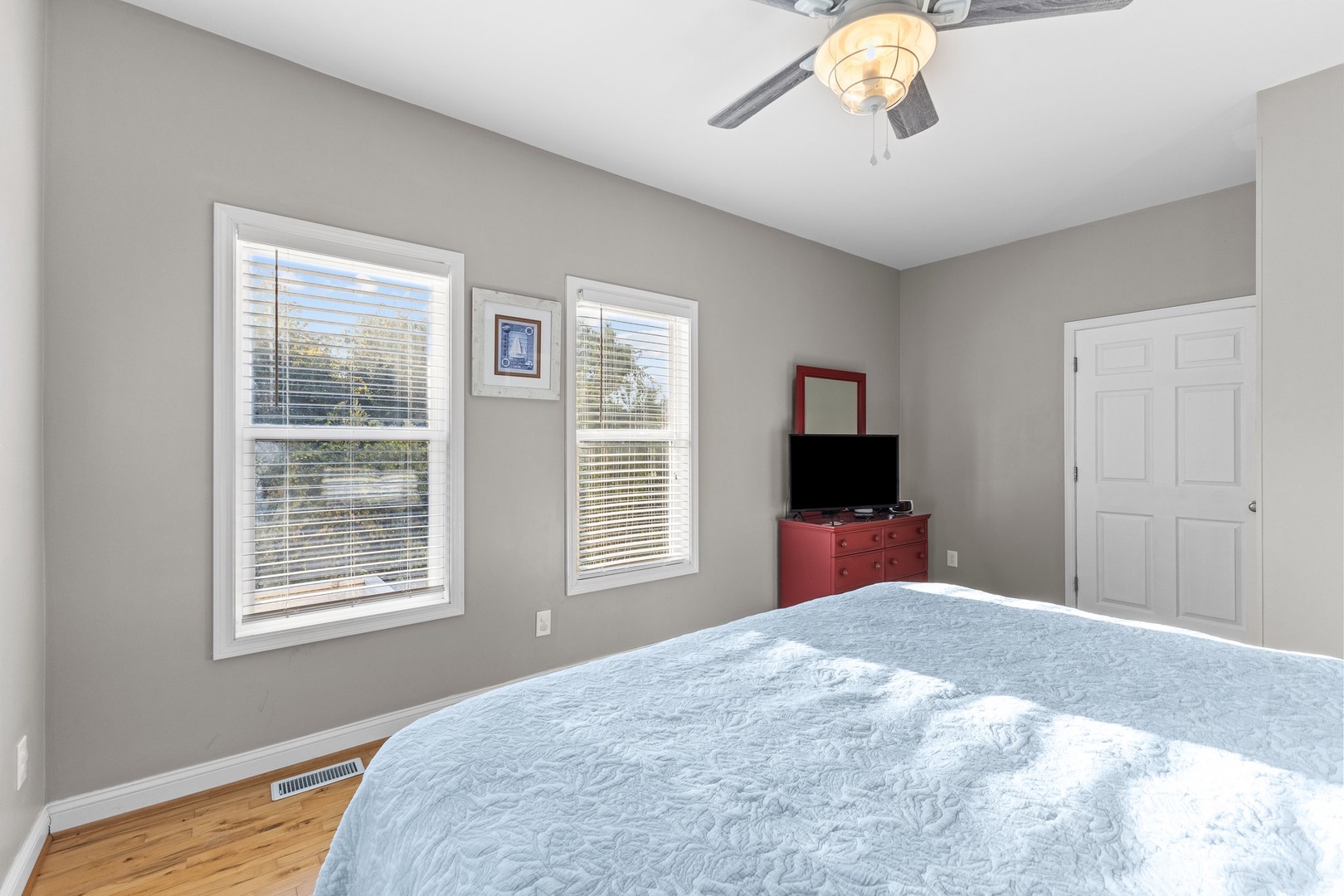 Relax in this peaceful bedroom with ceiling fan, smart TV entertainment, and large windows filling your space with natural light.