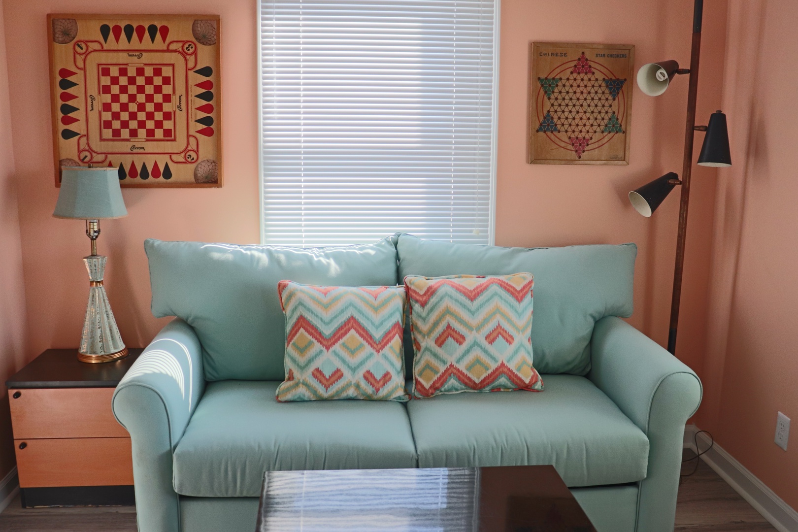 Settle into this charming living space where vintage game boards and soft mint seating create your perfect relaxation retreat.