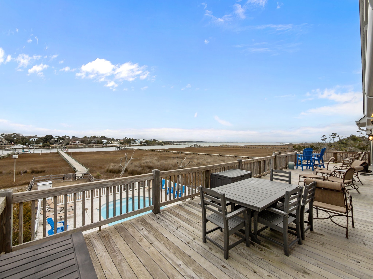 Expansive deck overlooks coastal marshlands and swimming pool, providing scenic views of the waterfront community.