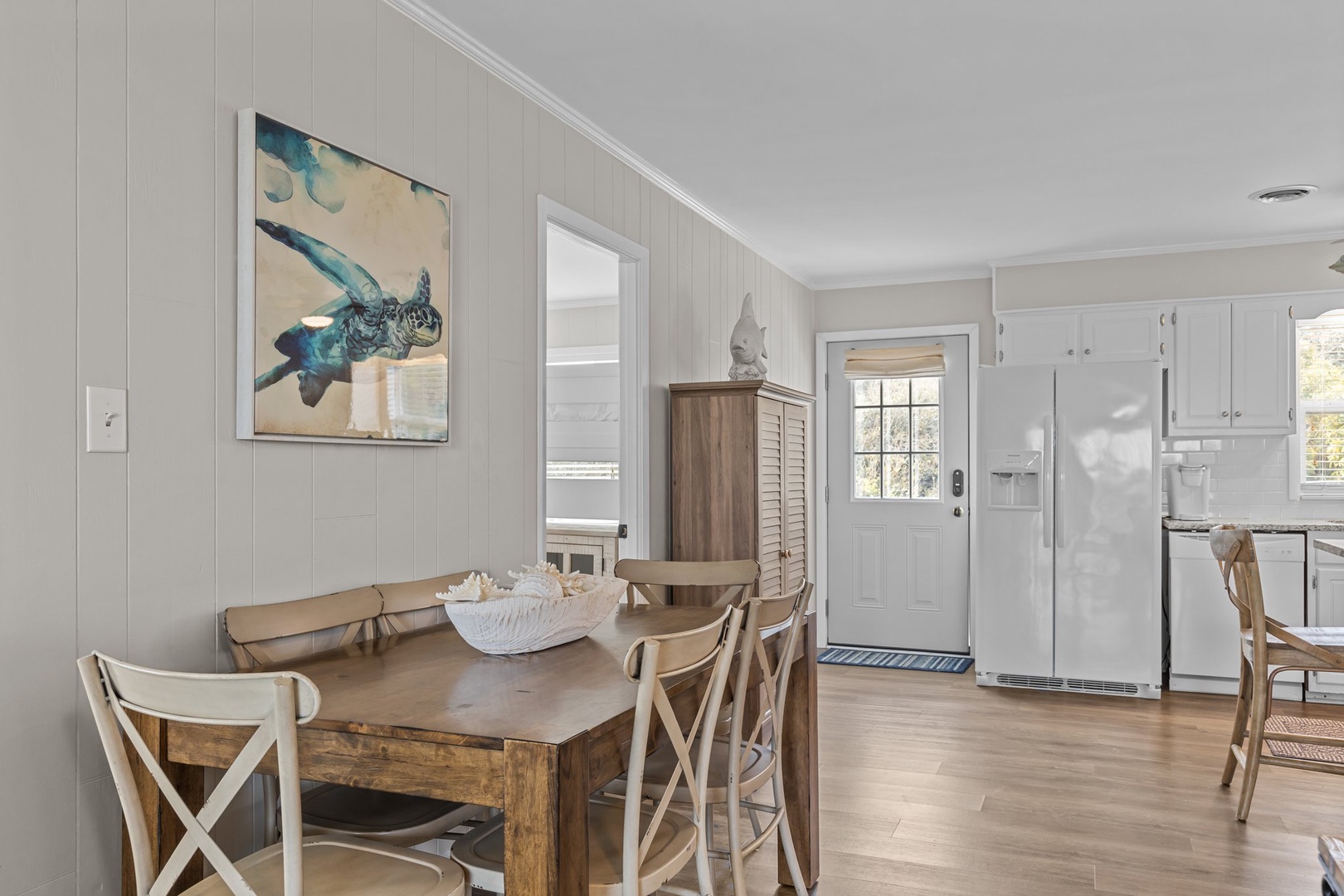Your coastal-themed dining space blends rustic charm with nautical touches, featuring a warm wood table perfect for gathering over home-cooked meals.