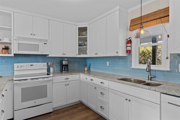 Your fully equipped kitchen features white cabinets, granite counters, and bright blue backsplash for easy meal prep.