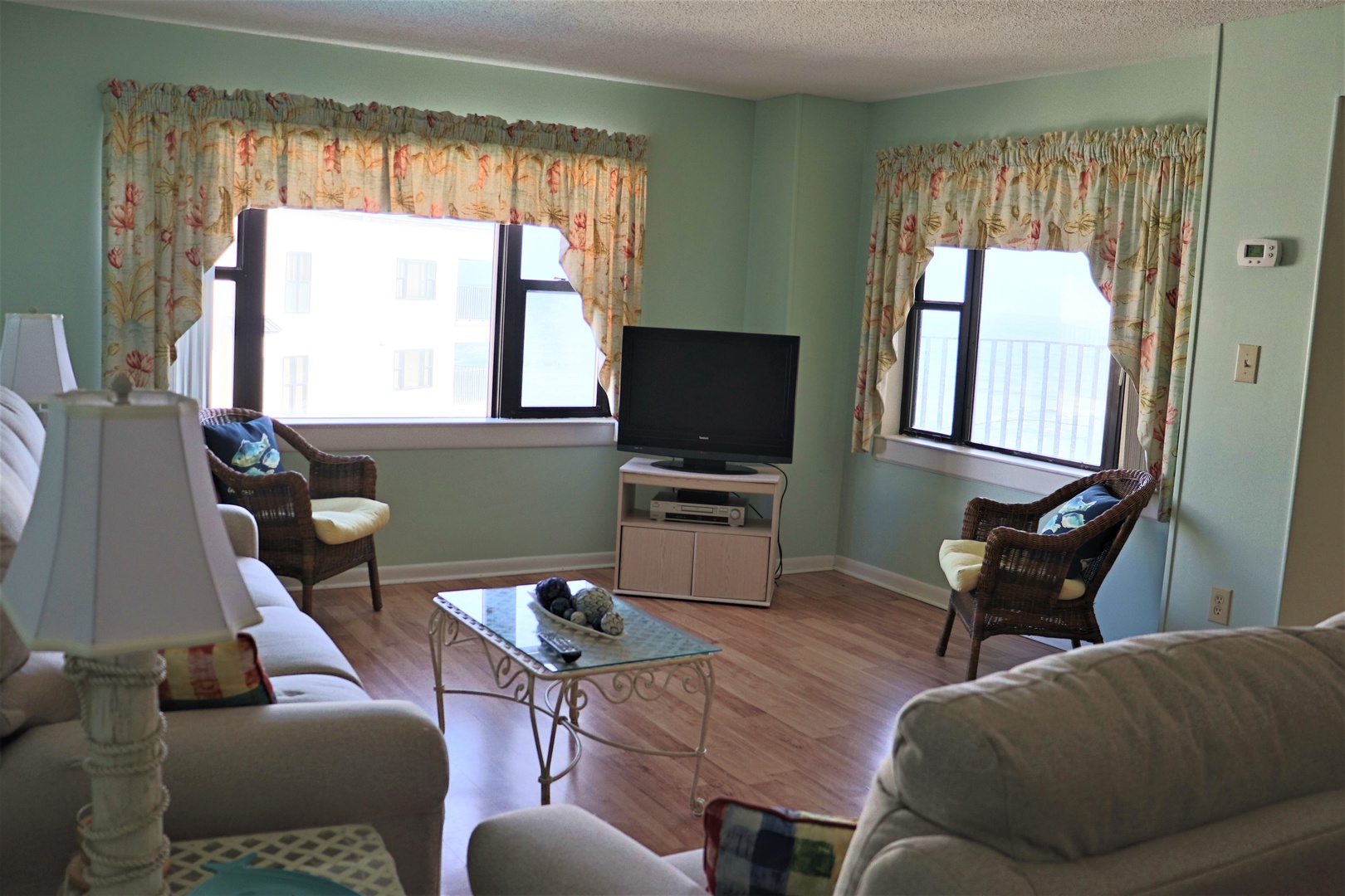 Relax in your bright living room with comfortable seating, tropical decor, and entertainment center perfect for unwinding.