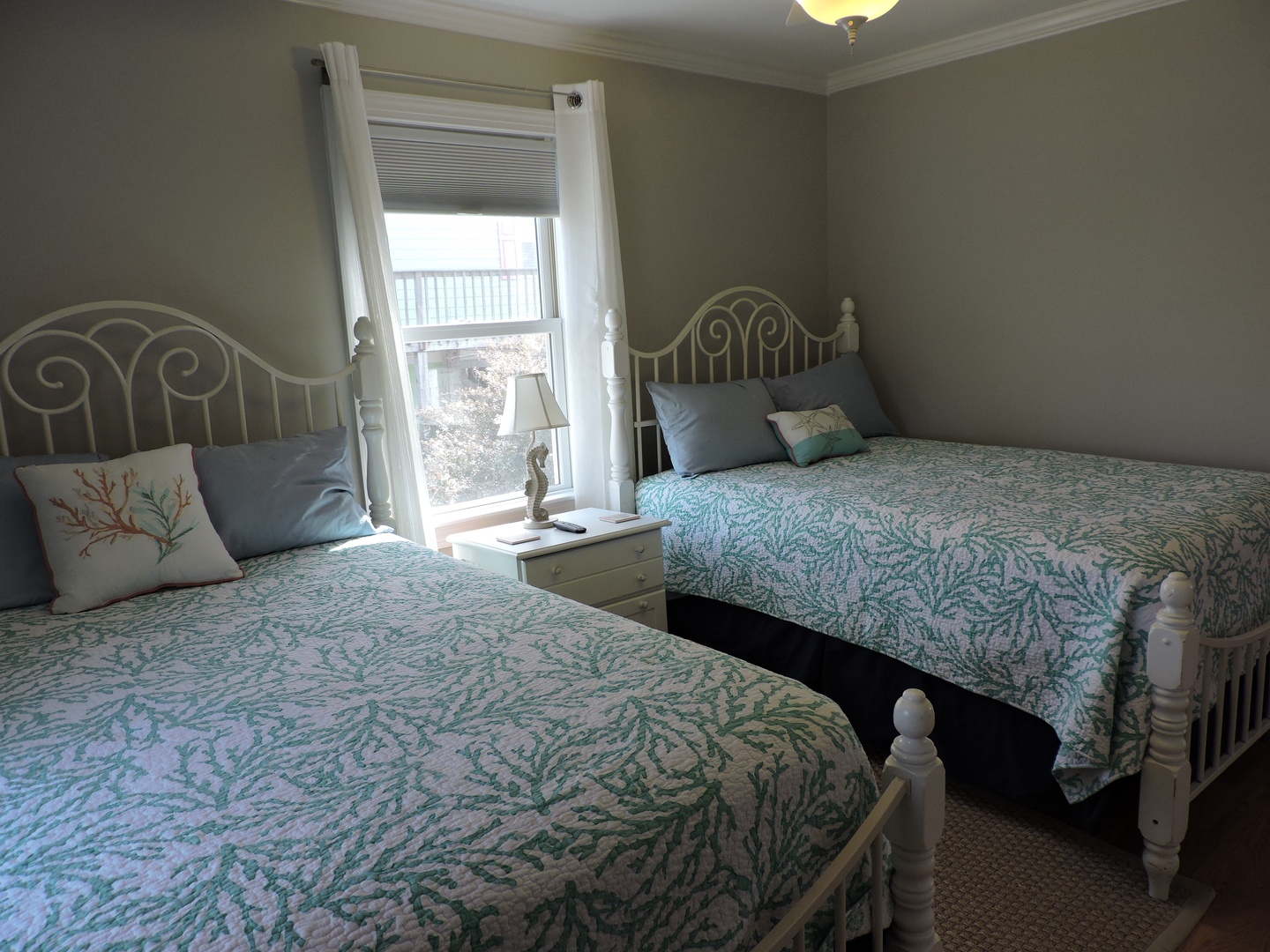 Rest peacefully in your coastal-themed twin bedroom with charming white iron beds and soft coral accent pillows.