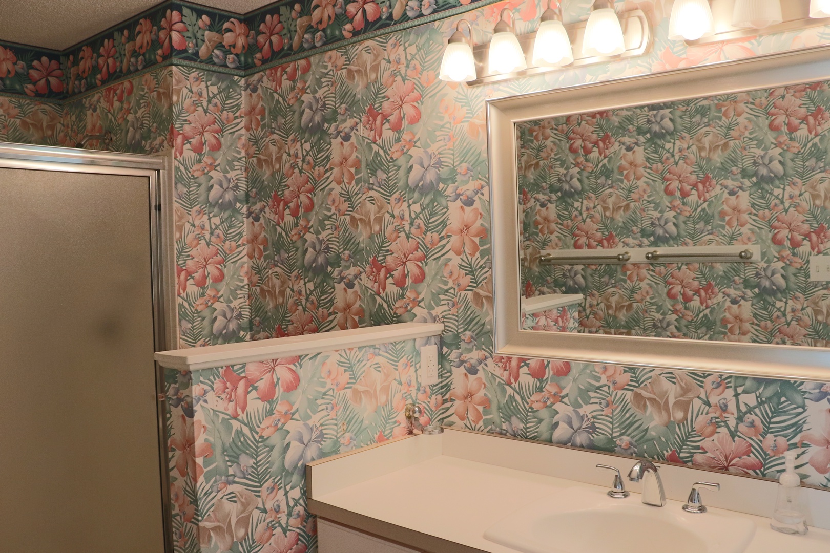 Step into your tropical-themed bathroom where vibrant floral wallpaper creates a cheerful, paradise-like atmosphere for your morning routine.