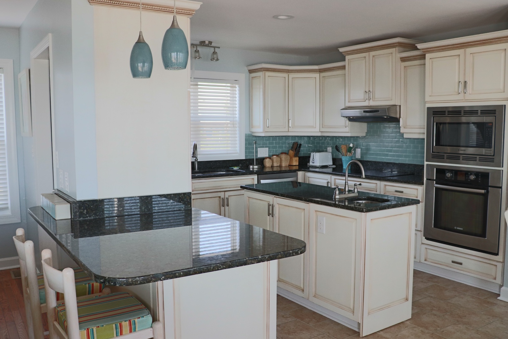 Your fully equipped kitchen features granite counters, stainless appliances, and coastal charm with turquoise accents for memorable meal prep.