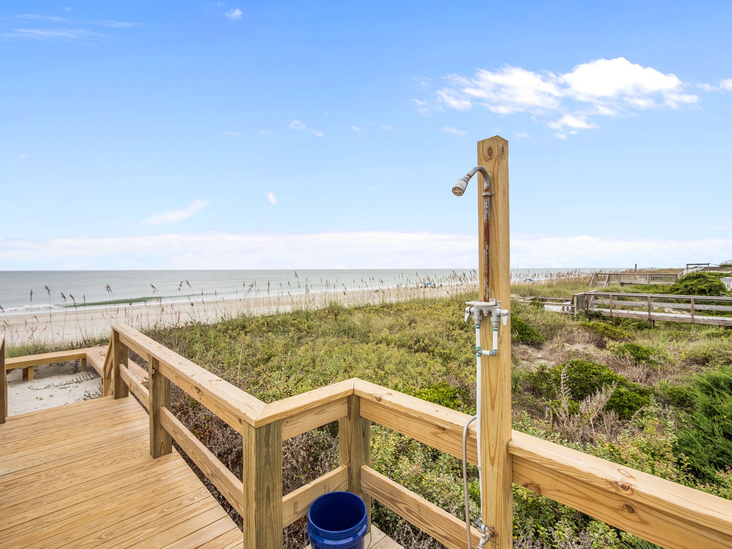 Beachfront boardwalk with outdoor shower station leads directly to pristine sandy shores and coastal dunes.