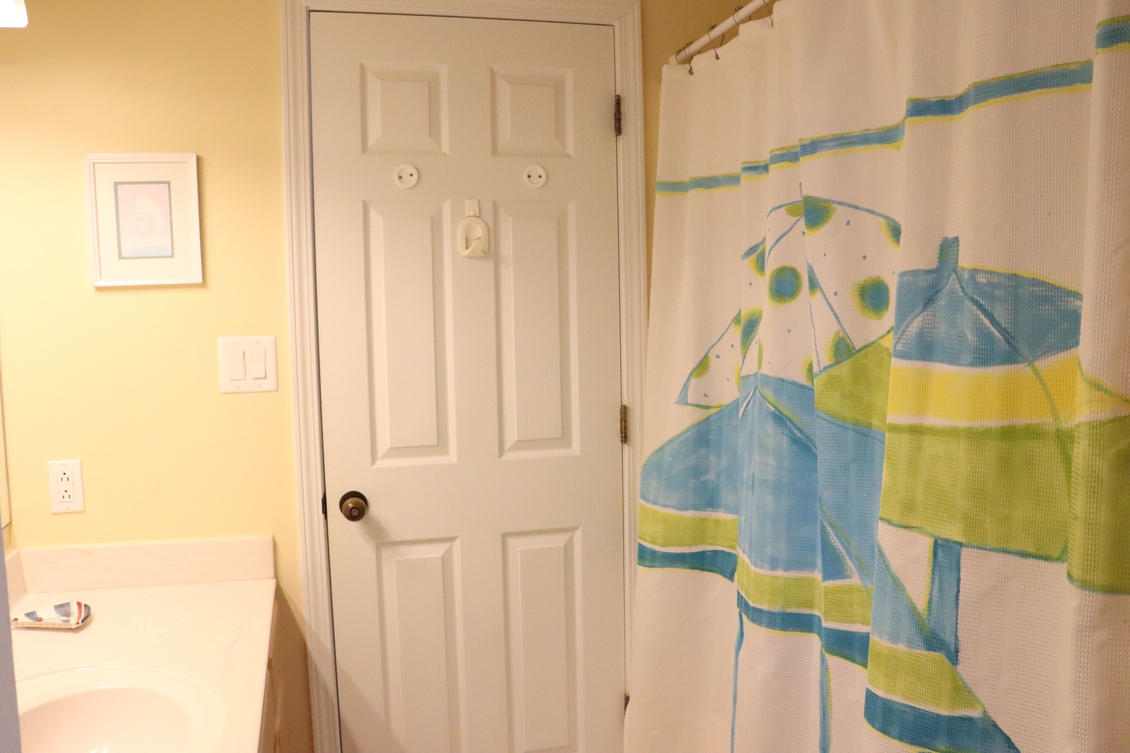 Your private bathroom features a cheerful shower with colorful curtain and warm yellow walls for a bright, refreshing start to your day.