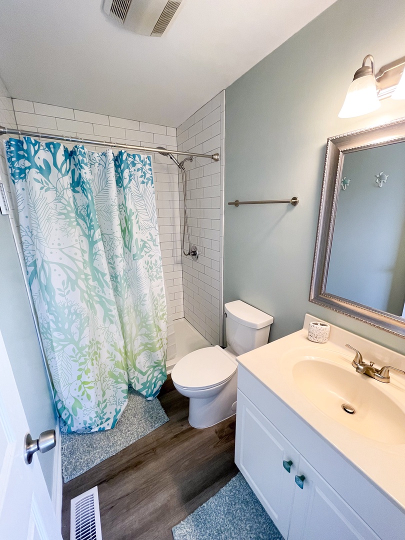 Refresh in your beautifully styled bathroom with tropical-inspired shower curtain, clean white subway tiles, and coastal decor touches.