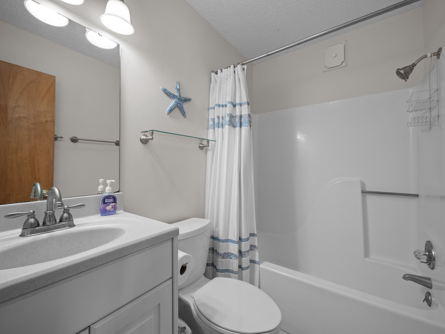 Your bright bathroom features a relaxing tub-shower combo with ocean-themed touches and everything you need for a refreshing stay.