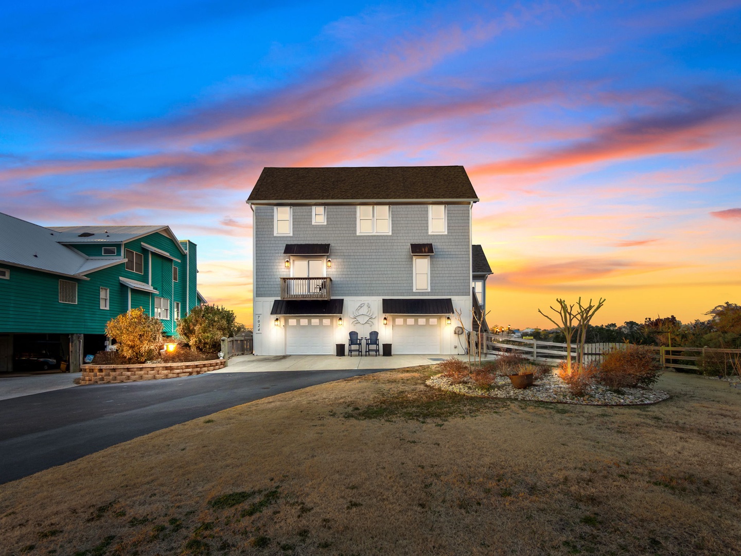 A charming coastal property at sunset showcasing modern beach architecture with elevated design and neighboring colorful homes.