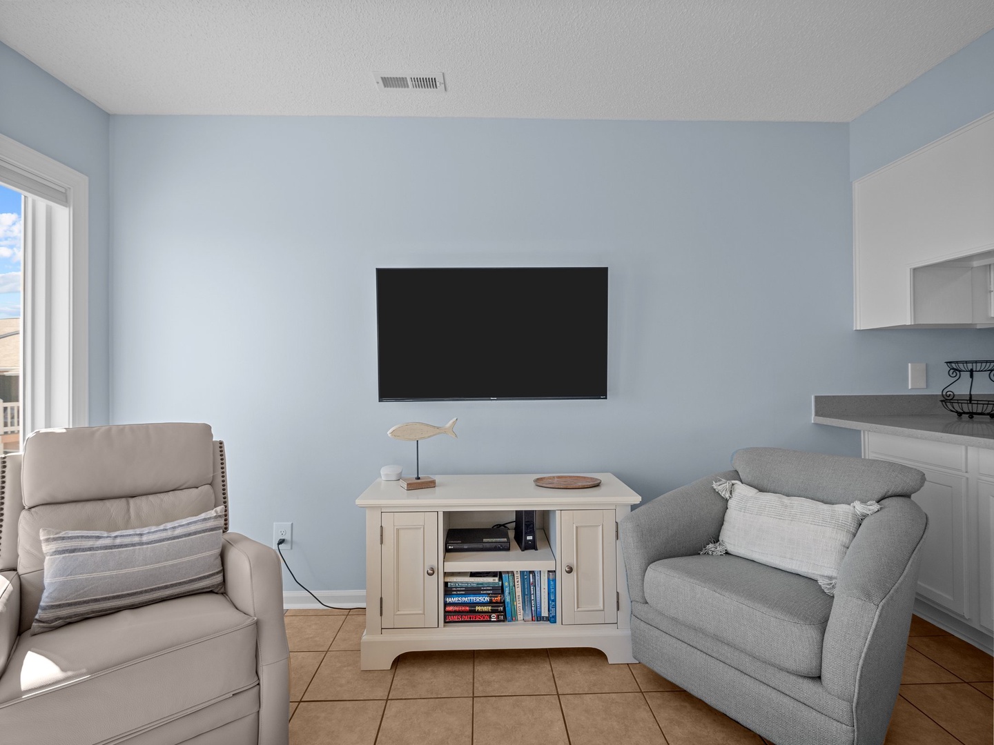 Unwind in your bright living space with comfortable seating, flat-screen TV, and charming coastal touches like the decorative fish accent.