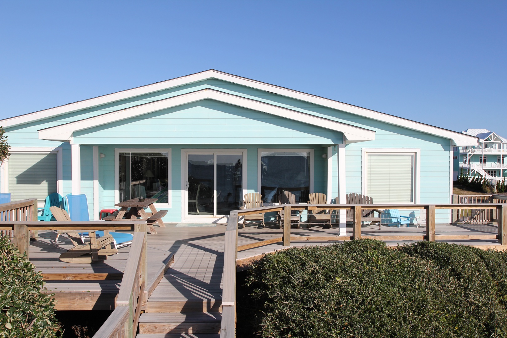 Charming beachside cottage with expansive wooden deck and outdoor furniture, perfect for coastal getaways.