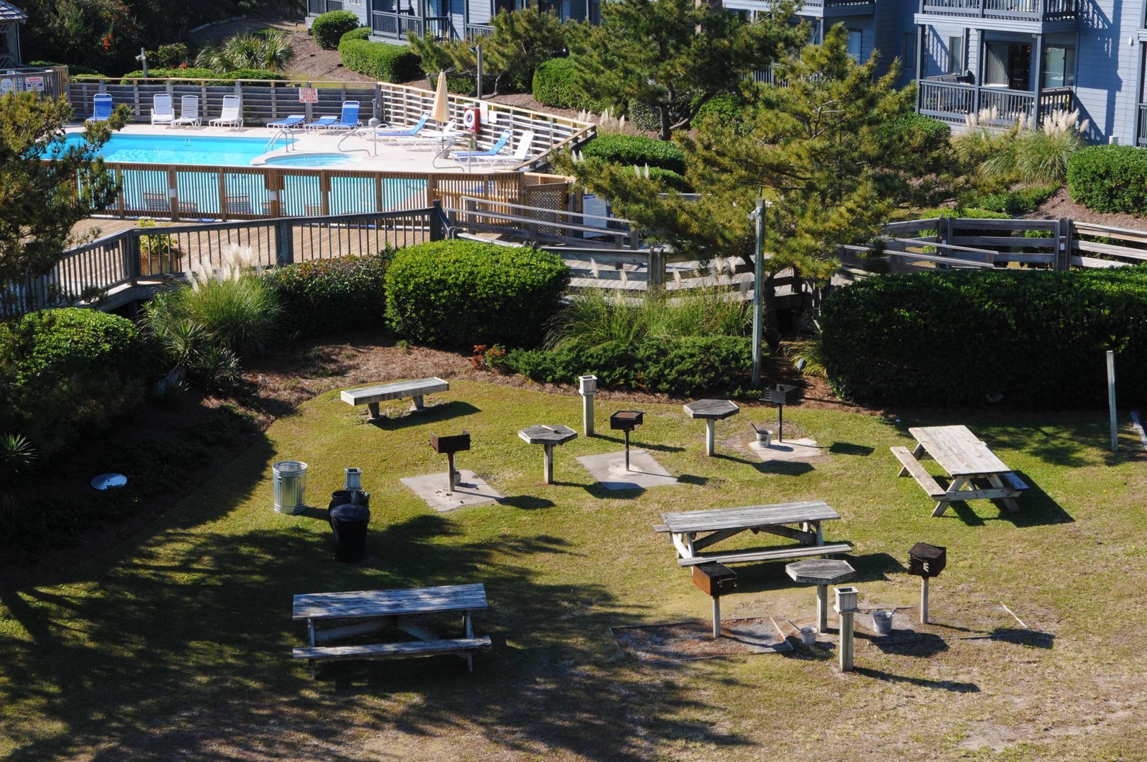 Gather around the communal BBQ area with picnic tables, grills, and lush garden surroundings—perfect for outdoor dining and socializing.