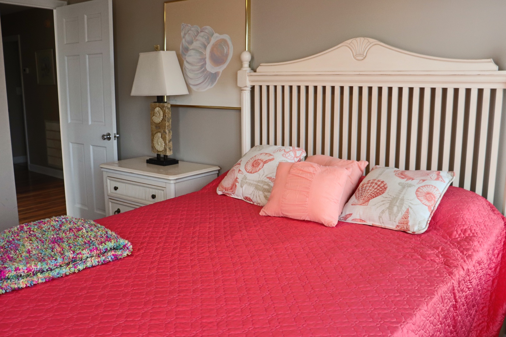 Sink into this cozy coastal bedroom where coral bedding and seashell accents create your perfect seaside retreat.