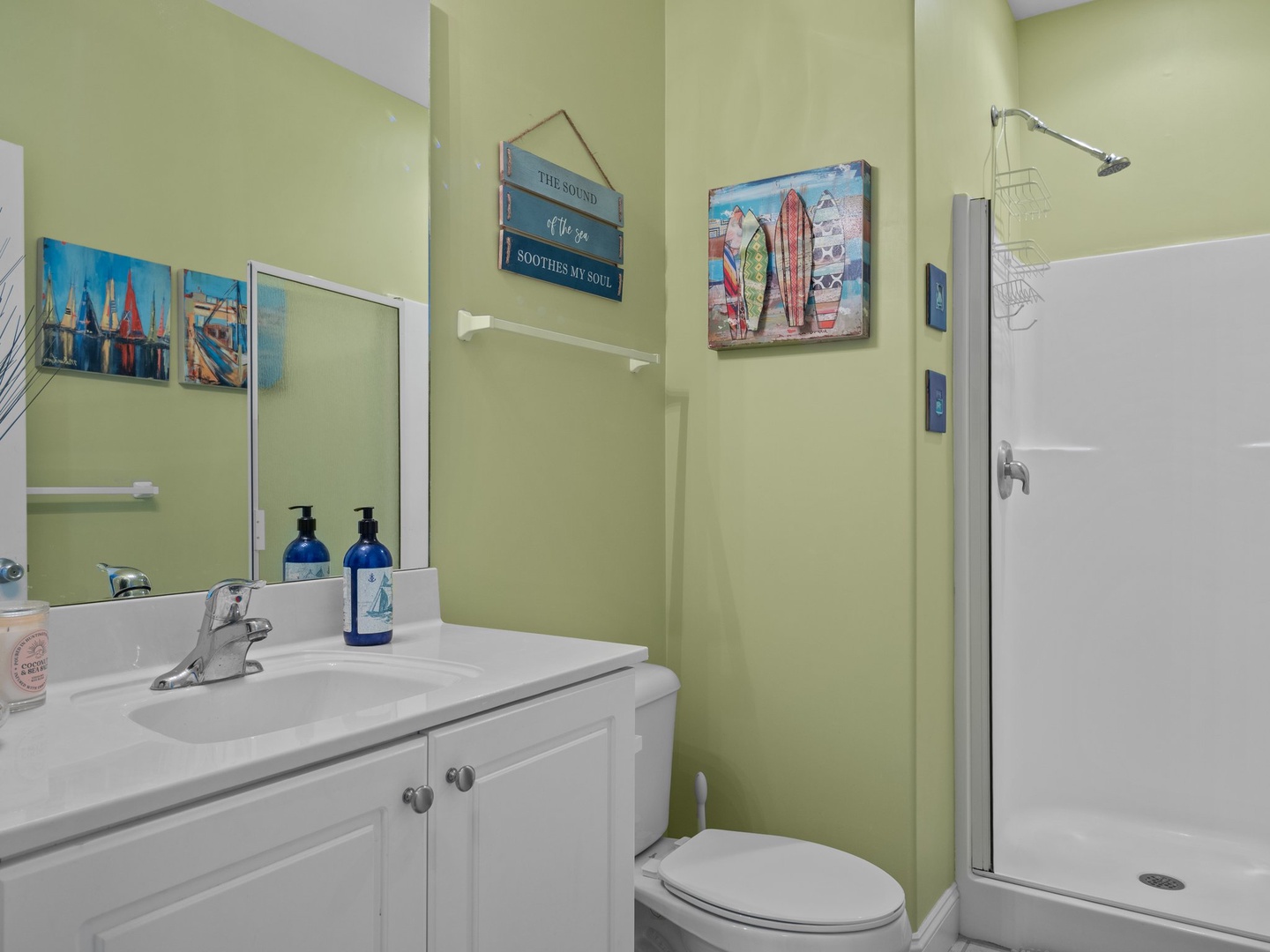 Refresh in your bright, coastal-themed bathroom with cheerful green walls, quality amenities, and beach-inspired art that sets the perfect vacation mood.