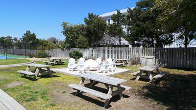 Spacious outdoor dining area with picnic tables and white chairs on sunny grounds, perfect for al fresco meals and gatherings.