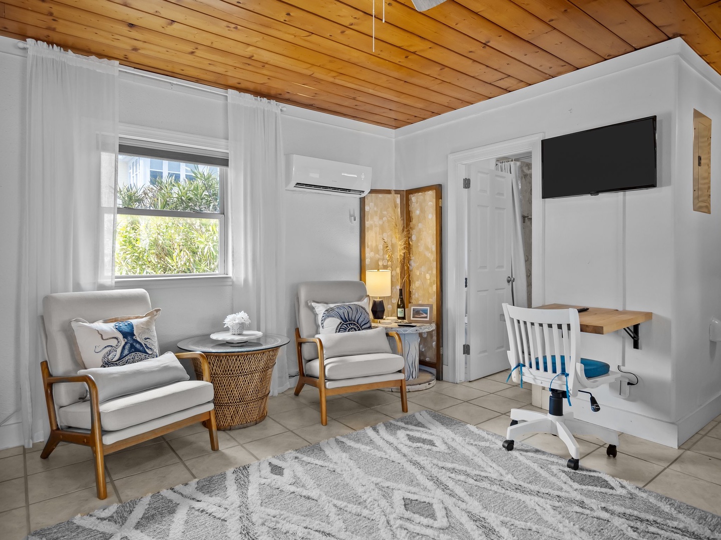 Relax in your bright living space with comfy chairs, warm wood ceiling, and workspace corner for productive moments.