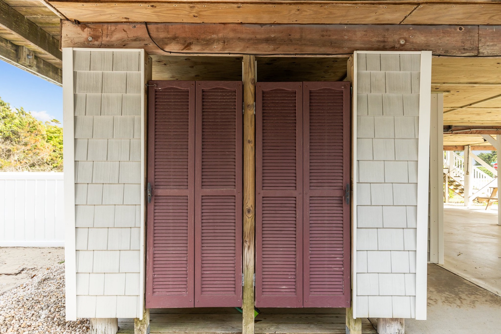 Your beachfront retreat features convenient outdoor storage with charming coastal-style doors, perfect for keeping beach gear organized and easily accessible.