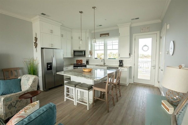 Your open-concept space blends coastal comfort with modern convenience, featuring a fully equipped kitchen island perfect for morning coffee and evening gatherings.