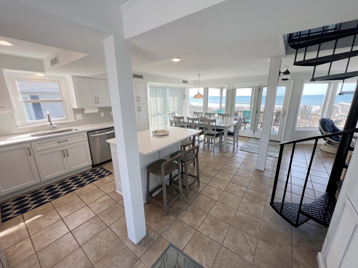 Your bright coastal kitchen flows seamlessly into dining space, with ocean views and island seating perfect for morning coffee or meal prep.