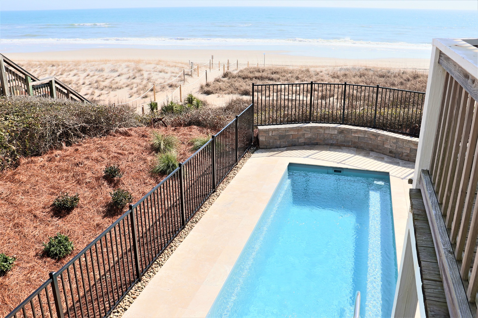 Stunning beachfront pool area with direct ocean access and panoramic coastal views.