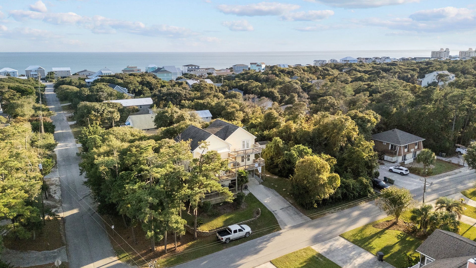 Elevated coastal community with beach access nearby and lush tree canopy throughout the residential area.