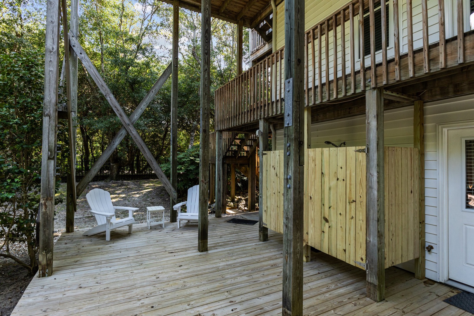 Relax on your private deck surrounded by nature, where wooden railings frame peaceful moments in white Adirondack chairs beneath leafy canopies.