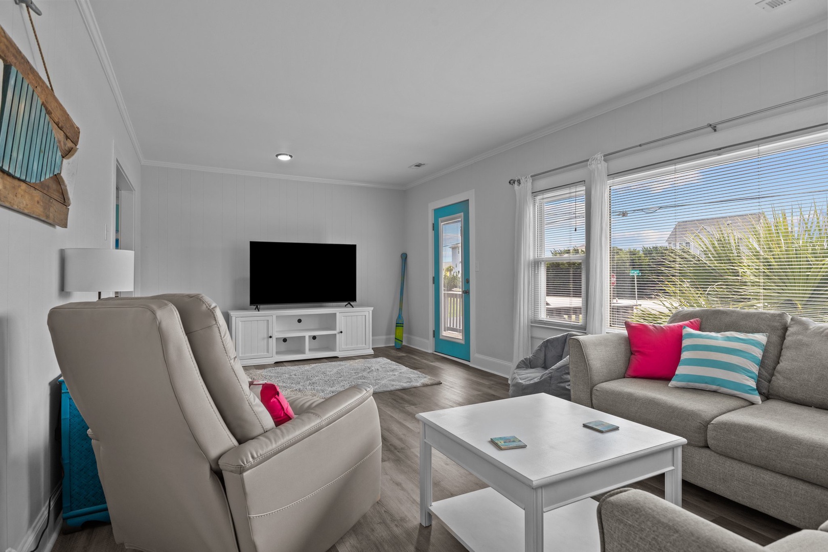 Unwind in your bright living room with cozy seating, entertainment setup, and colorful coastal touches that make relaxation effortless.